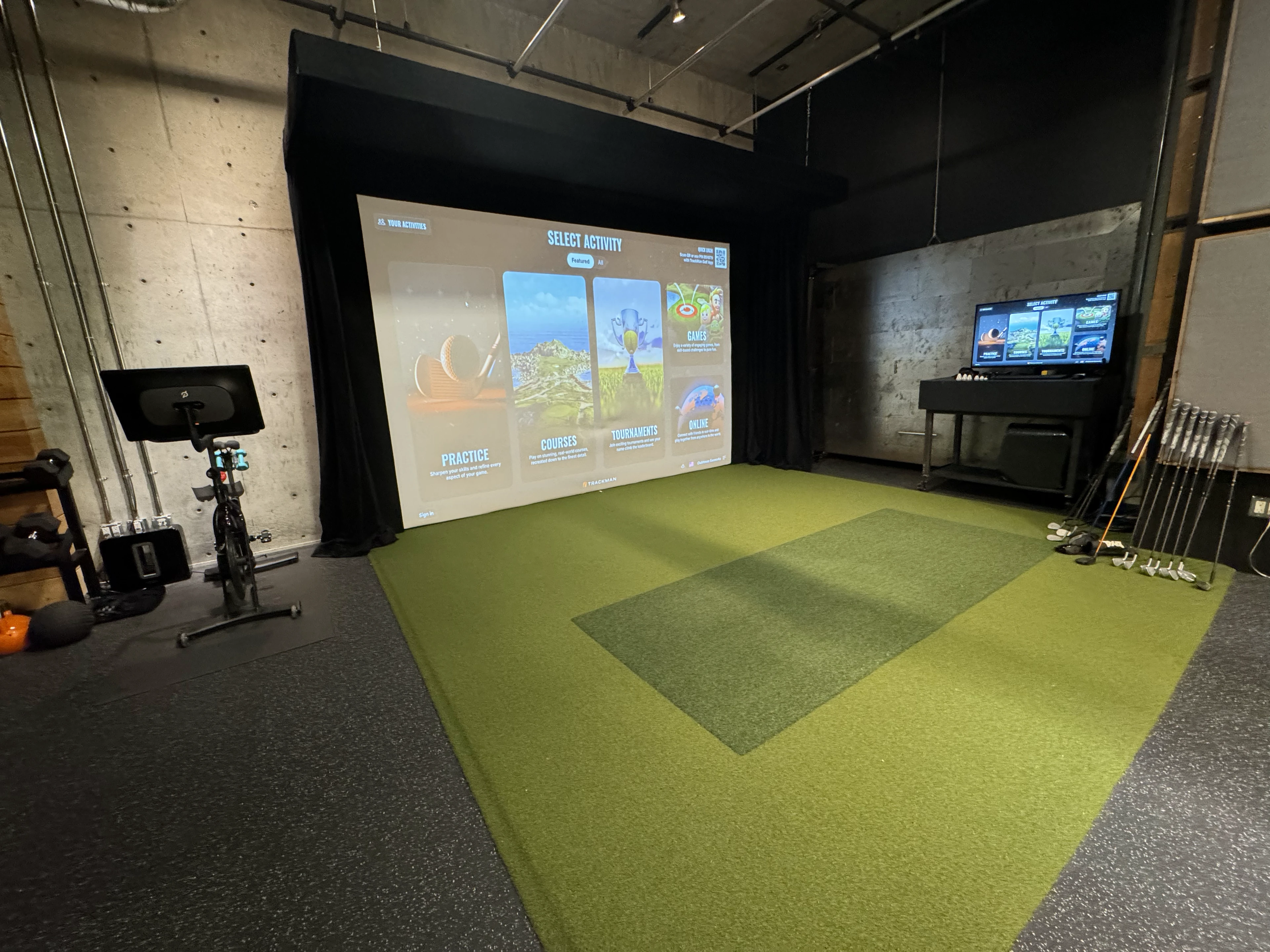 An indoor golf simulator with a projection screen and custom turf hitting area